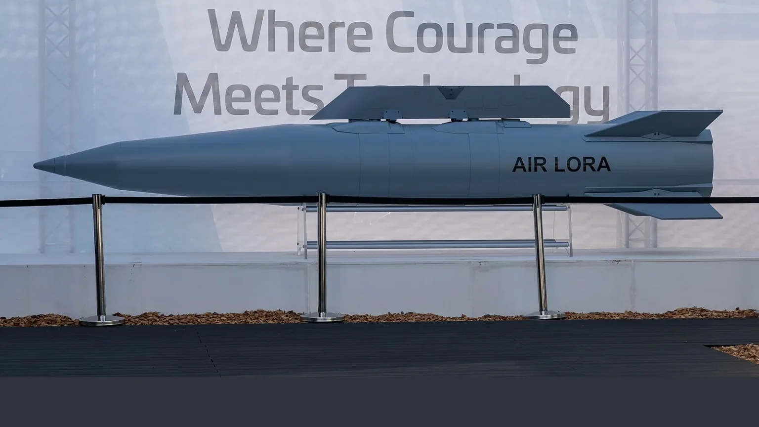 Γκρι βαλλιστικός πύραυλος με την επιγραφή AIR LORA εκτεθειμένος σε βάση πίσω από κορδόνι