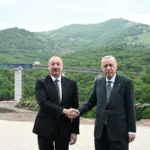 Ο Ιλχάμ Αλίγιεφ και ο Ρετζέπ Ταγίπ Ερντογάν δίνουν τα χέρια μπροστά σε γέφυρα αυτοκινητόδρομου σε ορεινή περιοχή