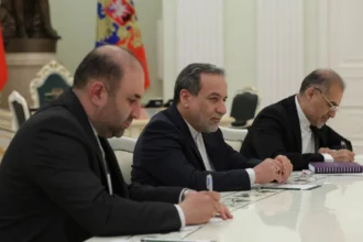 Ο Αμπάς Αραγτσί με σκούρο κοστούμι κάθεται σε τραπέζι συνομιλιών ανάμεσα σε μέλη αντιπροσωπείας
