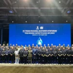 Αρχηγοί ναυτικών και σύνεδροι σε ομαδική φωτογραφία μπροστά σε οθόνη με τίτλο XV Trans-Regional Seapower Symposium