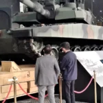 Τουρκικό άρμα μάχης Altay με παραλλαγή σε εκθεσιακό χώρο, με δύο επισκέπτες μπροστά του