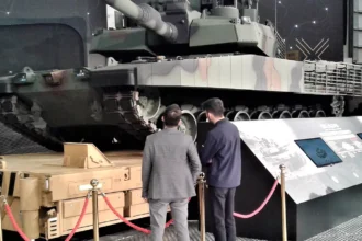 Τουρκικό άρμα μάχης Altay με παραλλαγή σε εκθεσιακό χώρο, με δύο επισκέπτες μπροστά του