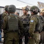 Ισραηλινοί στρατιώτες με πλήρη εξάρτυση συσκέπτονται σε δρόμο κατά την επιχείρηση στην περιοχή της Χεβρώνας