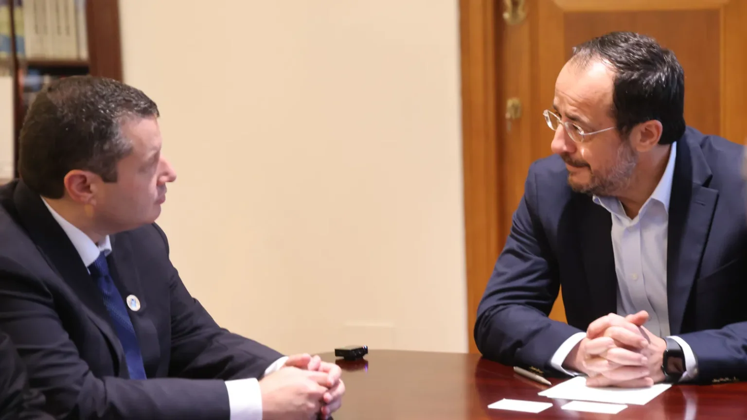 Ο Νίκος Χριστοδουλίδης σε συνάντηση στο Προεδρικό Μέγαρο, καθισμένος σε ξύλινο τραπέζι