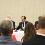 Ο Πρόεδρος της Κύπρου Νίκος Χριστοδουλίδης μιλά σε τραπέζι με μικρόφωνο, με ακροατές σε πρώτο πλάνο