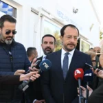 Ο Πρόεδρος της Κυπριακής Δημοκρατίας Νίκος Χριστοδουλίδης με σκούρο κοστούμι μιλά σε δημοσιογράφους που κρατούν μικρόφωνα