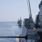 Πολεμικά πλοία πλέουν σε φάλαγγα στην Ανατολική Μεσόγειο κατά την άσκηση EUNOMIA 7-26, με πυροβόλο πλοίου σε πρώτο πλάνο