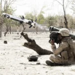 Στρατιώτης εκτοξεύει από τον ώμο αντιαρματικό πύραυλο Javelin σε ξηρό τοπίο με δέντρα