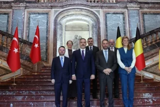 Ο Χακάν Φιντάν με Τούρκους και Βέλγους υπουργούς σε μαρμάρινη σκάλα ανάμεσα σε τουρκικές και βελγικές σημαίες