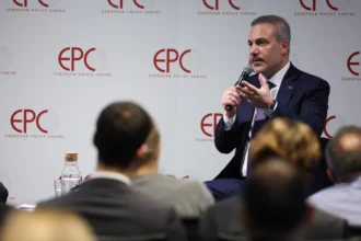Ο Χακάν Φιντάν μιλά σε μικρόφωνο καθισμένος μπροστά σε πάνελ με το λογότυπο EPC, με κοινό σε πρώτο πλάνο