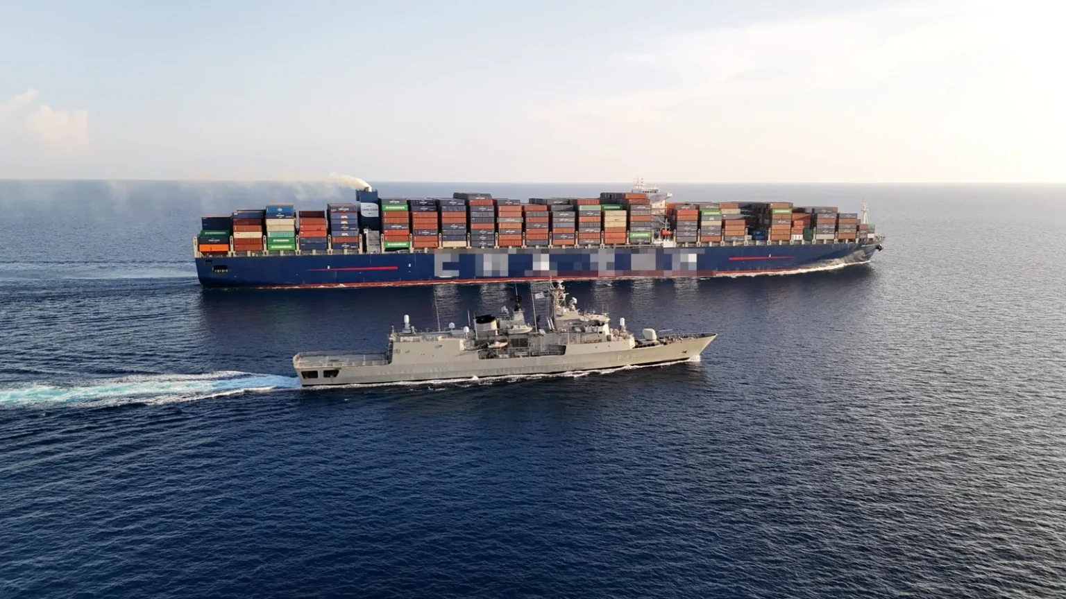 Η φρεγάτα «Σπέτσαι» (F-453) του Πολεμικού Ναυτικού πλέει δίπλα σε εμπορικό πλοίο μεταφοράς εμπορευματοκιβωτίων