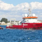 Λευκό και πορτοκαλί ερευνητικό σκάφος βγαίνει από λιμάνι