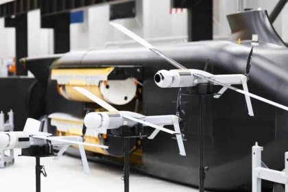 Λευκά drones ALTIUS με ανοιχτές έλικες σε βάσεις μπροστά σε μαύρο υποβρύχιο όχημα Ghost Shark με ανοιχτό χώρο φορτίου