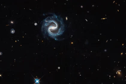 Εικόνα του Hubble με σπειροειδή γαλαξία με ράβδο στο κέντρο και βαρυτικό φακό στην κάτω δεξιά γωνία