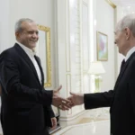 Ο Ιρανός πρόεδρος Μασούντ Πεζεσκιάν χαμογελά καθώς χαιρετά τον Βλαντιμίρ Πούτιν σε διάδρομο κτιρίου