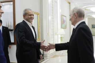 Ο Ιρανός πρόεδρος Μασούντ Πεζεσκιάν χαμογελά καθώς χαιρετά τον Βλαντιμίρ Πούτιν σε διάδρομο κτιρίου