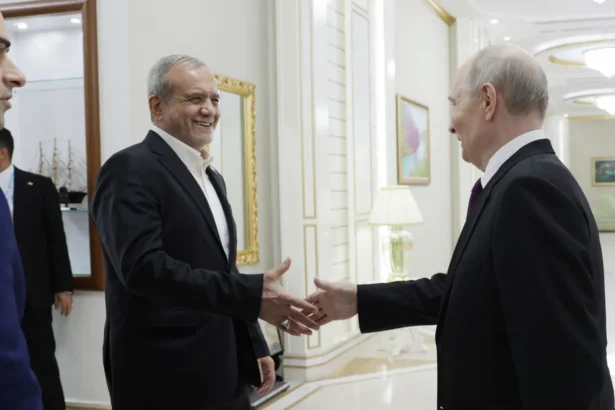 Ο Ιρανός πρόεδρος Μασούντ Πεζεσκιάν χαμογελά καθώς χαιρετά τον Βλαντιμίρ Πούτιν σε διάδρομο κτιρίου