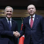 Ο Καναδός πρωθυπουργός Μαρκ Κάρνι και ο Τούρκος πρόεδρος Ρετζέπ Ταγίπ Ερντογάν δίνουν τα χέρια μπροστά σε καναδικές και τουρκικές σημαίες