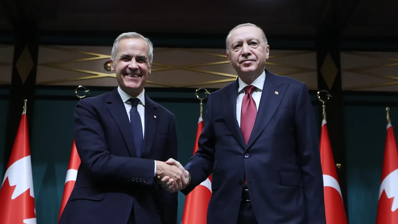 Ο Καναδός πρωθυπουργός Μαρκ Κάρνι και ο Τούρκος πρόεδρος Ρετζέπ Ταγίπ Ερντογάν δίνουν τα χέρια μπροστά σε καναδικές και τουρκικές σημαίες