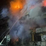Διασώστες σβήνουν φωτιά σε κατεστραμμένη πολυκατοικία στο Κίεβο τη νύχτα