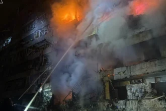 Διασώστες σβήνουν φωτιά σε κατεστραμμένη πολυκατοικία στο Κίεβο τη νύχτα