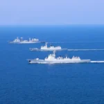 Τρία γκρι πολεμικά πλοία του κινεζικού ναυτικού πλέουν σε σχηματισμό σε γαλάζια θάλασσα