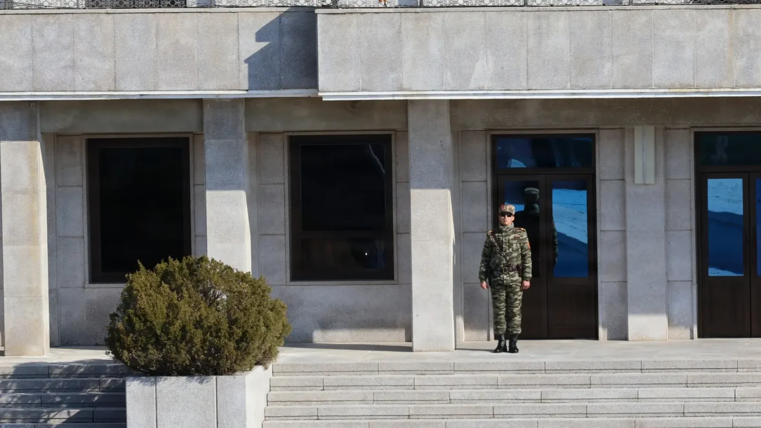 Βορειοκορεάτης στρατιώτης σε σκοπιά μπροστά από κτίριο στη βόρεια πλευρά της Αποστρατιωτικοποιημένης Ζώνης στο Πανμουντζόμ