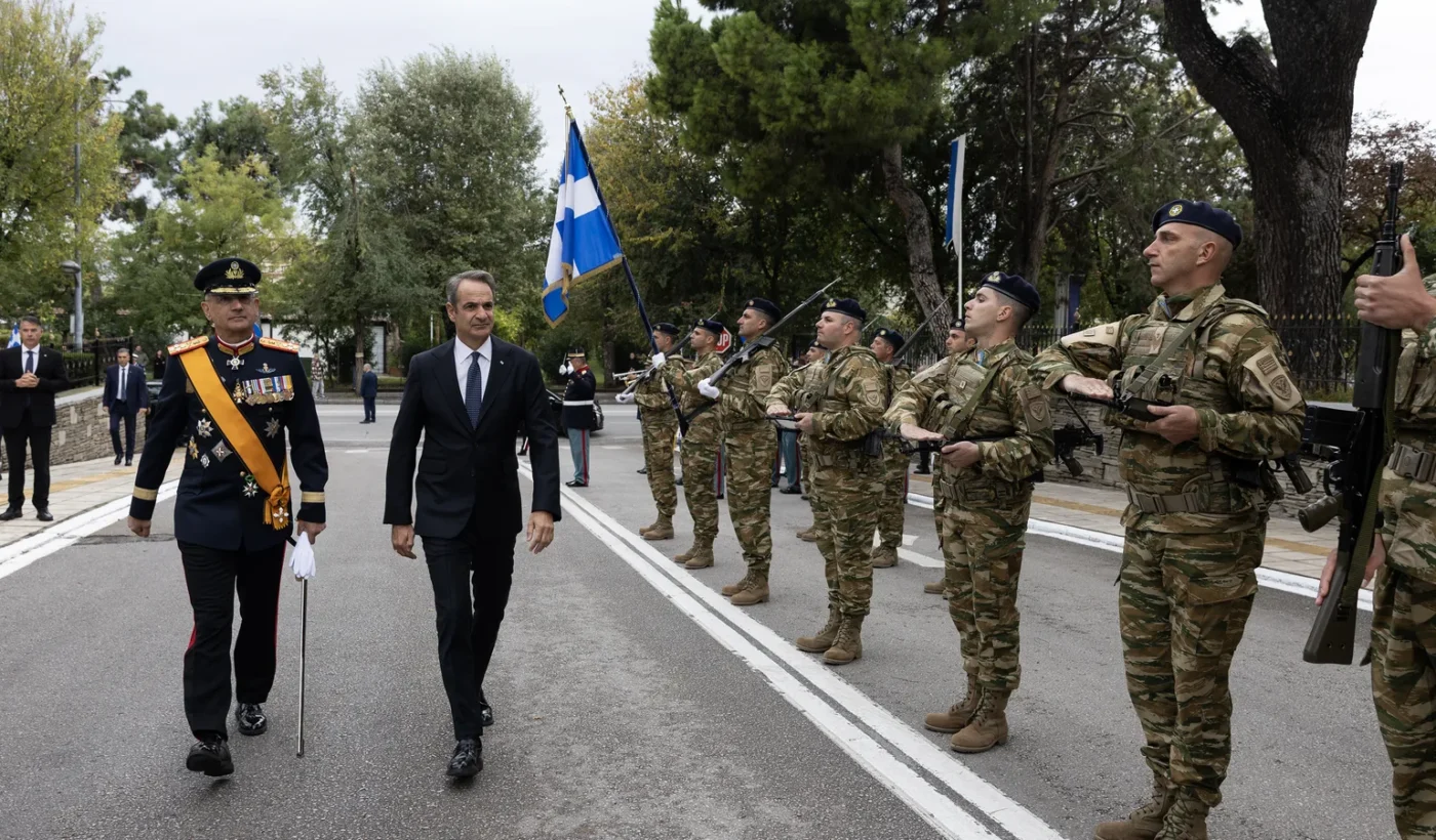 Ο πρωθυπουργός Κυριάκος Μητσοτάκης περνά μπροστά από άγημα στρατιωτών με παραλλαγή, συνοδευόμενος από αξιωματικό με επίσημη στολή