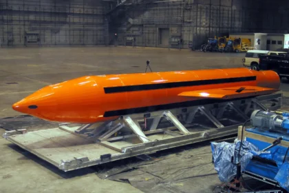 Πορτοκαλί βόμβα GBU-43/B MOAB πάνω σε μεταλλική βάση μεταφοράς μέσα σε υπόστεγο