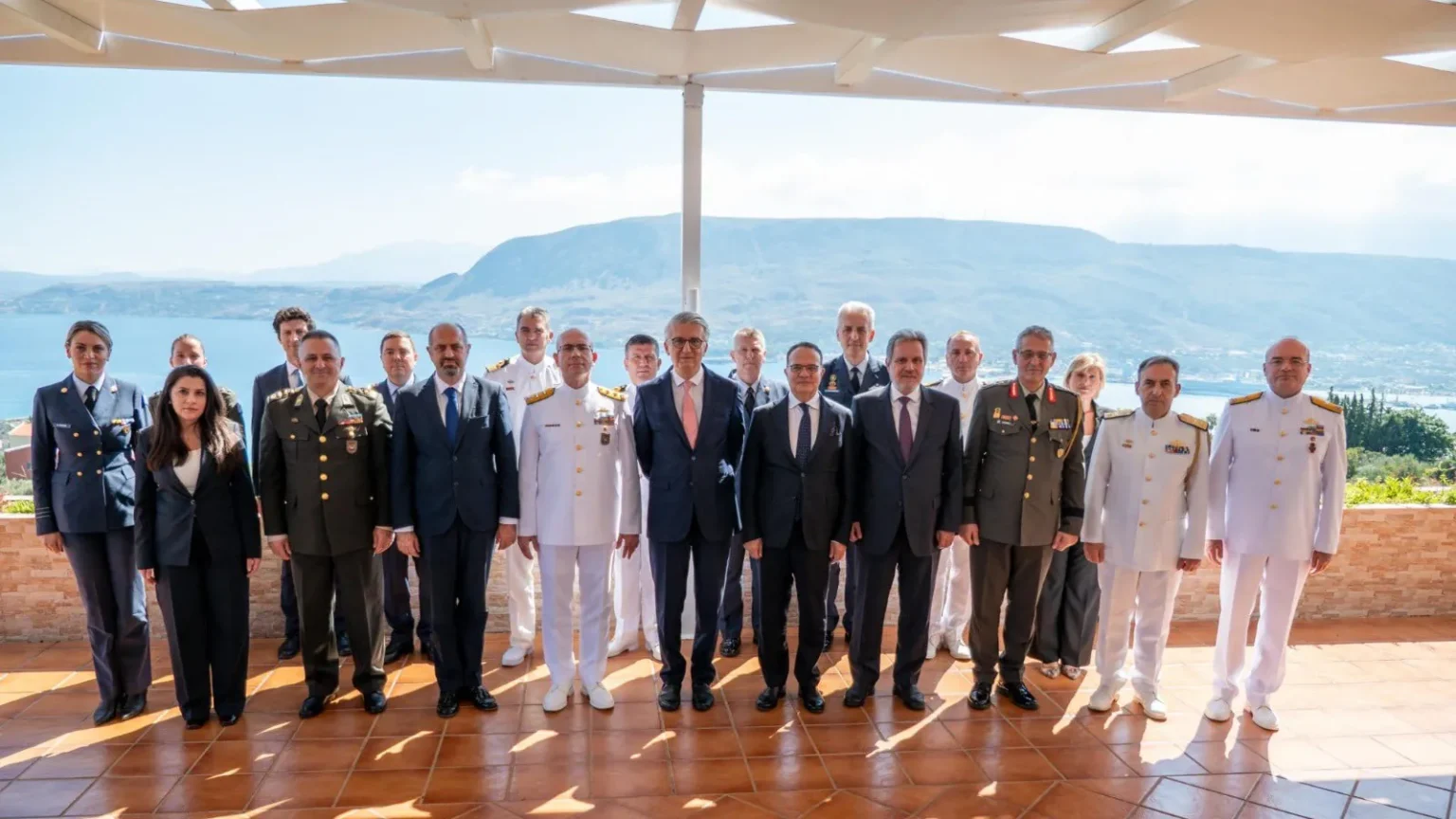 Ομαδική φωτογραφία στρατιωτικών και διπλωματών των αντιπροσωπειών Ελλάδας και Τουρκίας σε βεράντα με θέα στη θάλασσα στα Χανιά