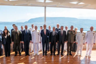 Ομαδική φωτογραφία στρατιωτικών και διπλωματών των αντιπροσωπειών Ελλάδας και Τουρκίας σε βεράντα με θέα στη θάλασσα στα Χανιά