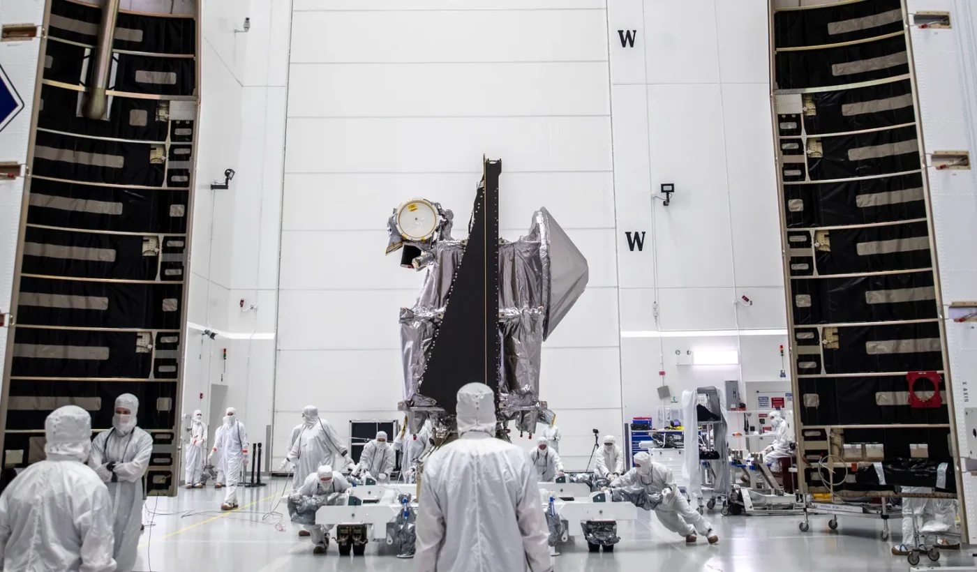 Το διαστημόπλοιο Lucy της NASA με τους τεχνικούς γύρω του, ανάμεσα στα δύο μισά του προστατευτικού καλύμματος του πυραύλου, στις εγκαταστάσεις Astrotech