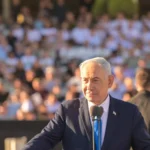 Ο πρωθυπουργός του Ισραήλ Μπενιαμίν Νετανιάχου μιλά από βήμα σε υπαίθρια τελετή με πλήθος στο βάθος