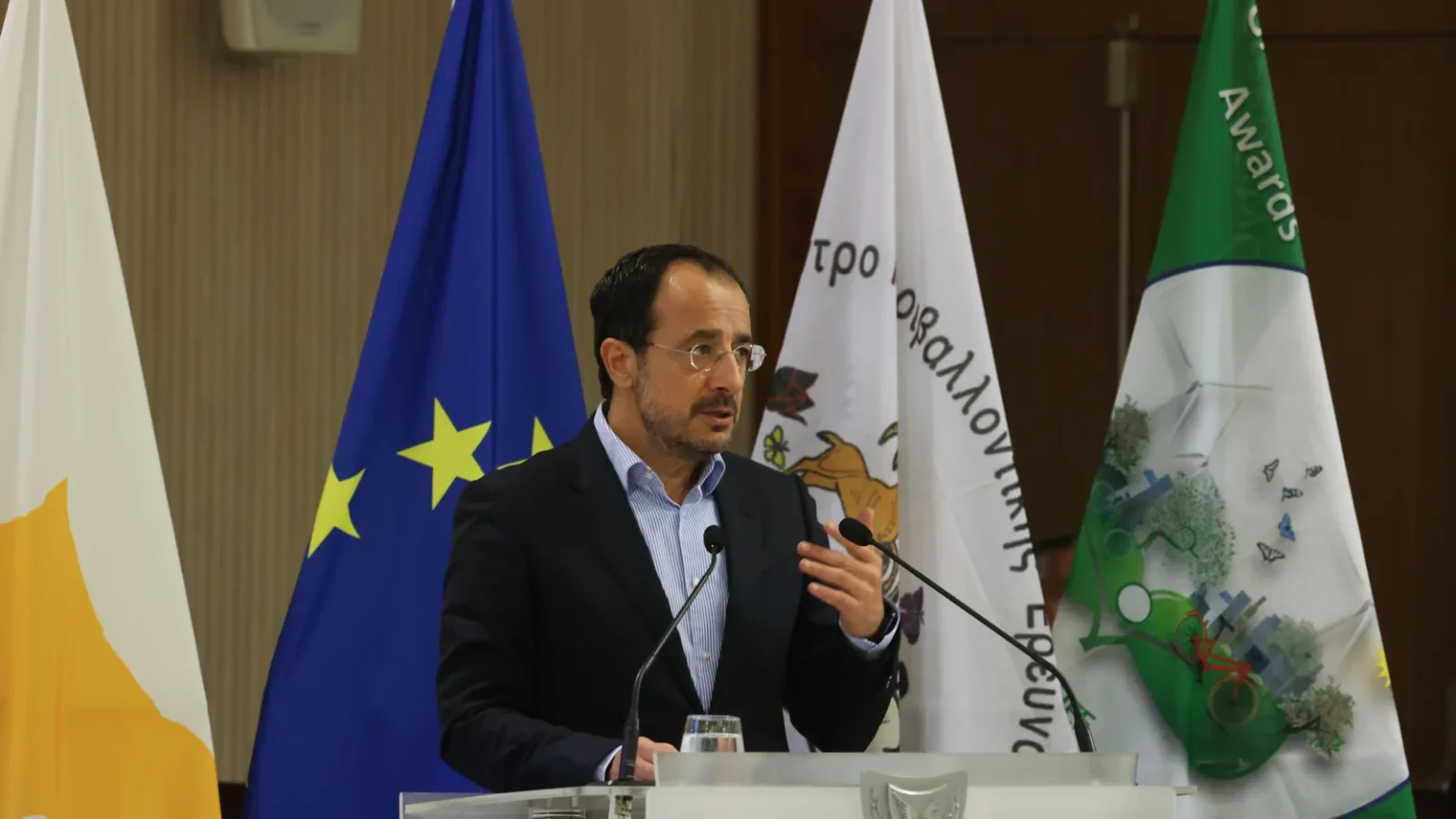 Ο Πρόεδρος της Κυπριακής Δημοκρατίας Νίκος Χριστοδουλίδης μιλά σε βήμα με τις σημαίες της Κύπρου και της Ευρωπαϊκής Ένωσης