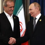 Ο Βλαντιμίρ Πούτιν και ο Μασούντ Πεζεσκιάν σφίγγουν τα χέρια μπροστά στις σημαίες Ρωσίας και Ιράν