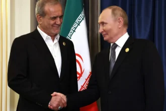 Ο Βλαντιμίρ Πούτιν και ο Μασούντ Πεζεσκιάν σφίγγουν τα χέρια μπροστά στις σημαίες Ρωσίας και Ιράν