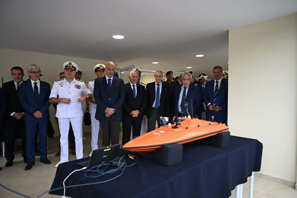 Ο Νίκος Δένδιας, ο Αρχηγός ΓΕΝ και προσκεκλημένοι μπροστά σε μικρό πορτοκαλί μη επανδρωμένο σκάφος με κάμερες