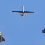 Δύο μαχητικά Rafale και ένα μη επανδρωμένο αερόχημα Reaper πετούν σε σχηματισμό, φωτογραφημένα από το έδαφος
