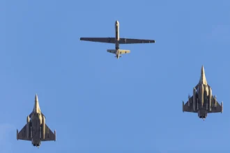 Δύο μαχητικά Rafale και ένα μη επανδρωμένο αερόχημα Reaper πετούν σε σχηματισμό, φωτογραφημένα από το έδαφος