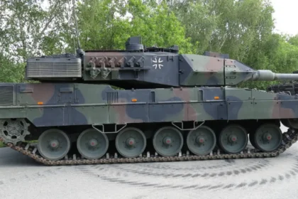 Πλάγια όψη άρματος μάχης Leopard 2A7 με παραλλαγή σε άσφαλτο, με δέντρα στο φόντο