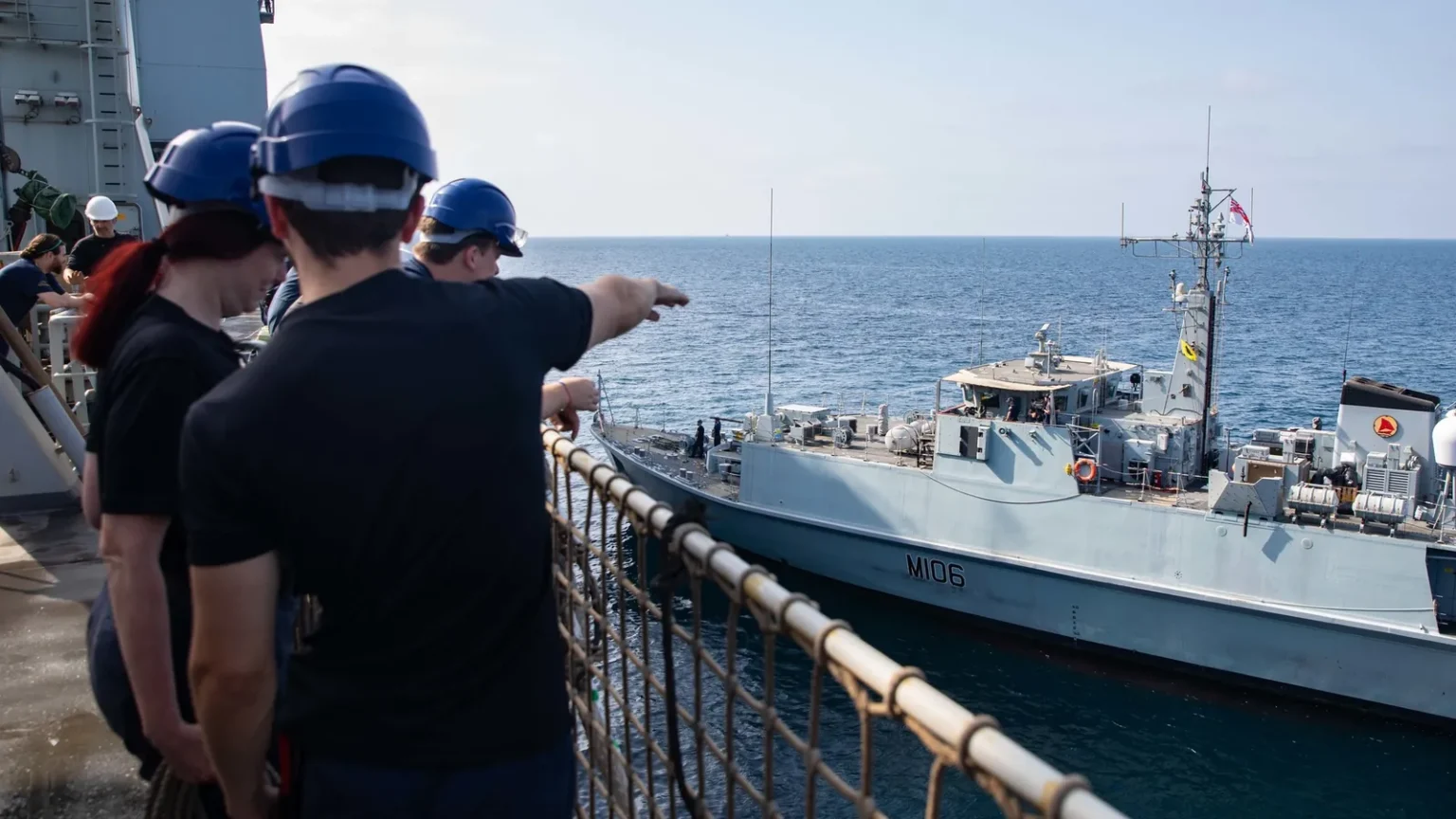 Βρετανοί ναυτικοί στο κατάστρωμα του RFA Lyme Bay δείχνουν το ναρκοθηρευτικό HMS Penzance (M106) που πλέει δίπλα τους στον Κόλπο του Ομάν