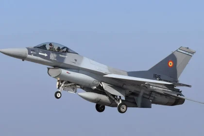 Γκρι μαχητικό F-16 με το ρουμανικό σήμα στο κάθετο σταθερό, σε πτήση με κατεβασμένα σκέλη προσγείωσης