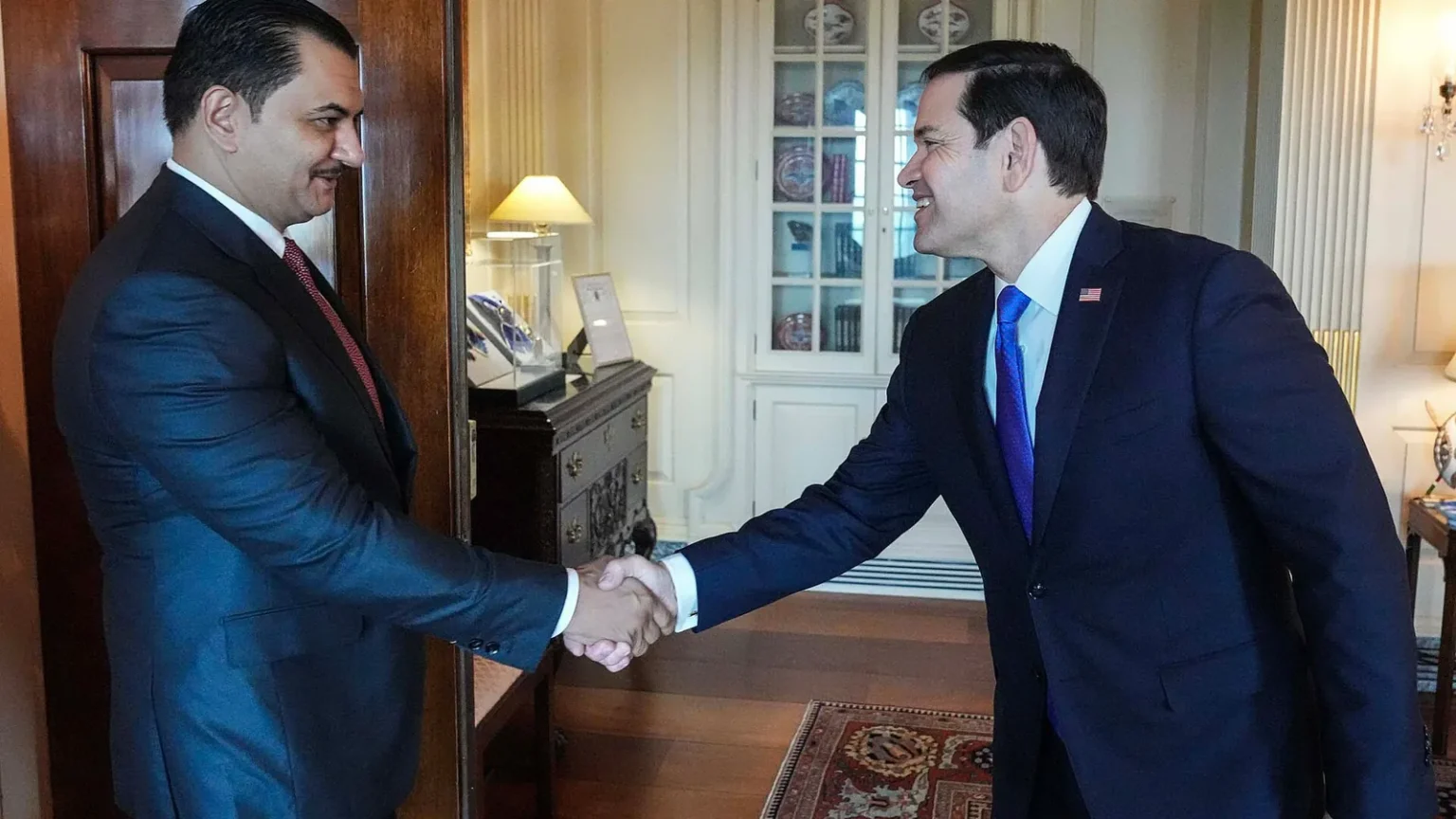 Ο Σαντάμ Χαφτάρ σφίγγει το χέρι του Αμερικανού υπουργού Εξωτερικών Μάρκο Ρούμπιο σε γραφείο με ξύλινη πόρτα και βιτρίνα