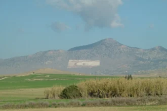 Τεράστιες σημαίες της Τουρκίας και του ψευδοκράτους σχηματισμένες στην πλαγιά του Πενταδάκτυλου, πίσω από πεδιάδα