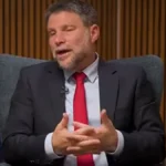 Ο Ισραηλινός υπουργός Οικονομικών Μπεζαλέλ Σμότριτς μιλά καθισμένος σε πολυθρόνα, με την ισραηλινή σημαία πίσω του