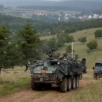 Τεθωρακισμένο όχημα Stryker 8×8 του Αμερικανικού Στρατού κινείται σε χωματόδρομο σε πράσινη κοιλάδα