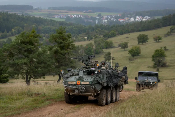 Τεθωρακισμένο όχημα Stryker 8×8 του Αμερικανικού Στρατού κινείται σε χωματόδρομο σε πράσινη κοιλάδα