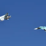 Ένα μαχητικό Su-35S και ένα μαχητικό-βομβαρδιστικό Su-34 της ρωσικής Αεροπορίας πετούν σε σχηματισμό σε καθαρό ουρανό