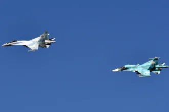 Ένα μαχητικό Su-35S και ένα μαχητικό-βομβαρδιστικό Su-34 της ρωσικής Αεροπορίας πετούν σε σχηματισμό σε καθαρό ουρανό