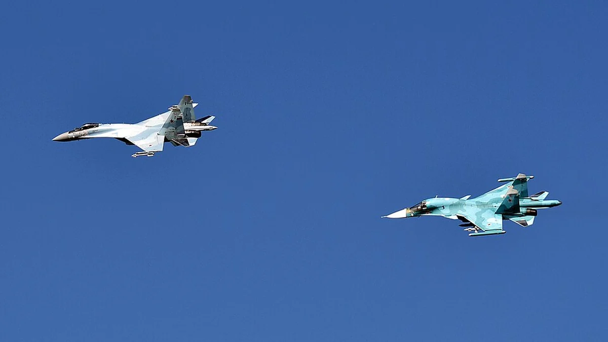 Ένα μαχητικό Su-35S και ένα μαχητικό-βομβαρδιστικό Su-34 της ρωσικής Αεροπορίας πετούν σε σχηματισμό σε καθαρό ουρανό